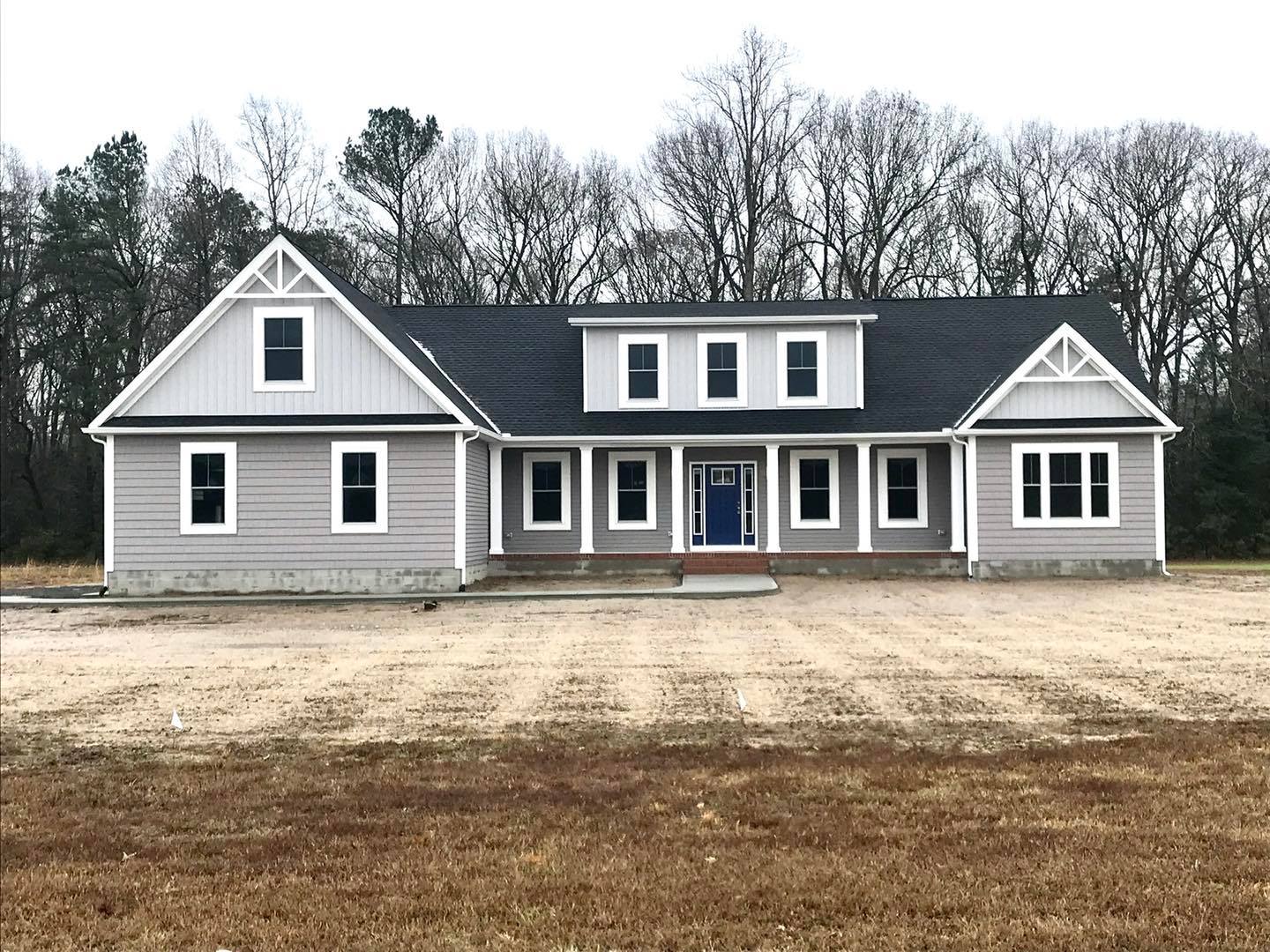a large gray house sitting in the middle of a field